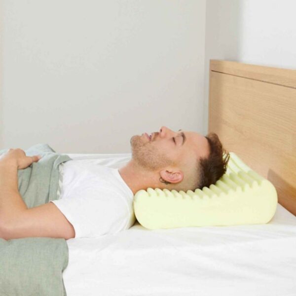 Man lying on a bed with a therapeutic sleeprrr memory foam pillow under his head.